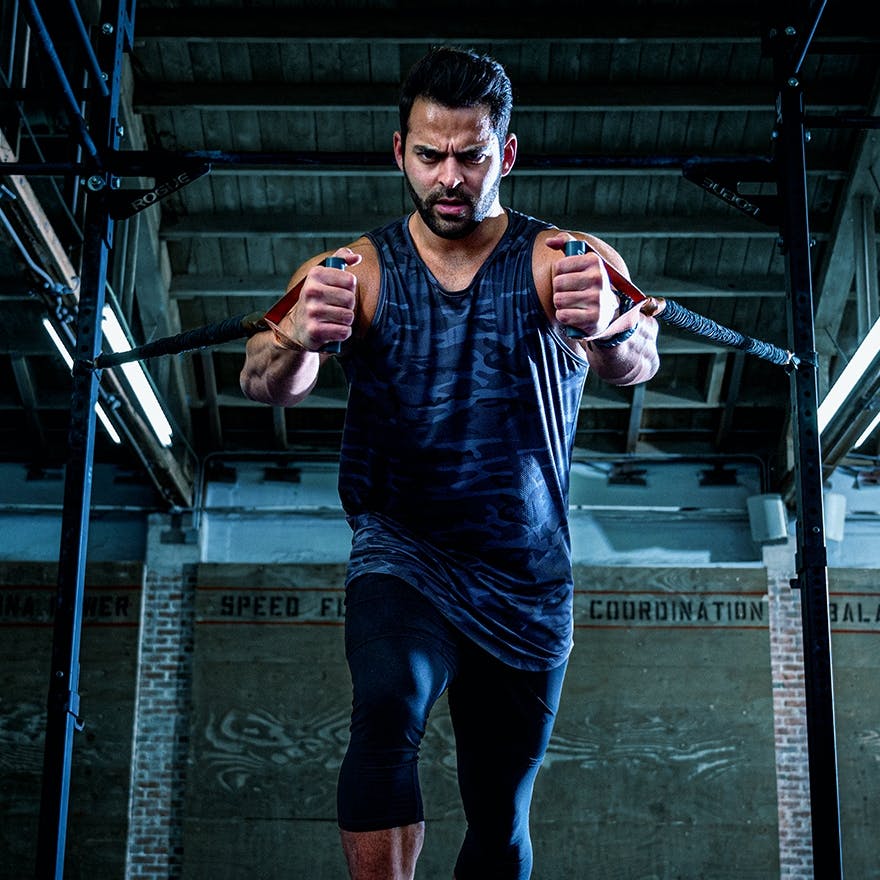 A man in a gym, pulling on some weight rings.