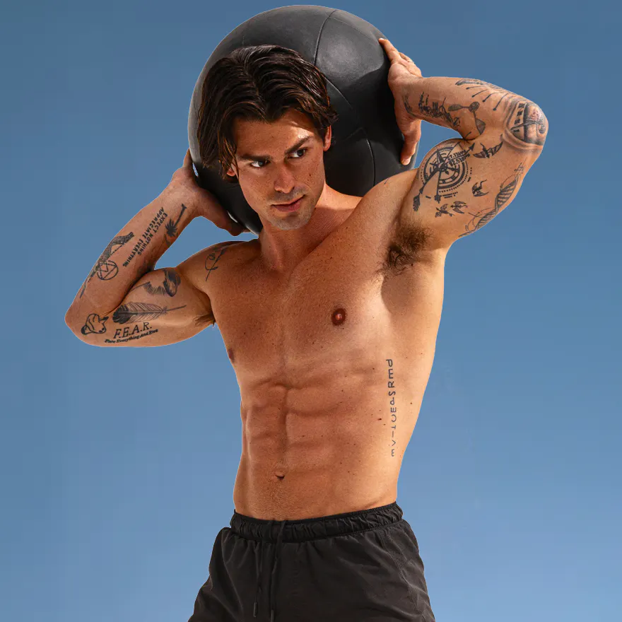 A photo of Garret Miller holding a medicine ball high above his head.