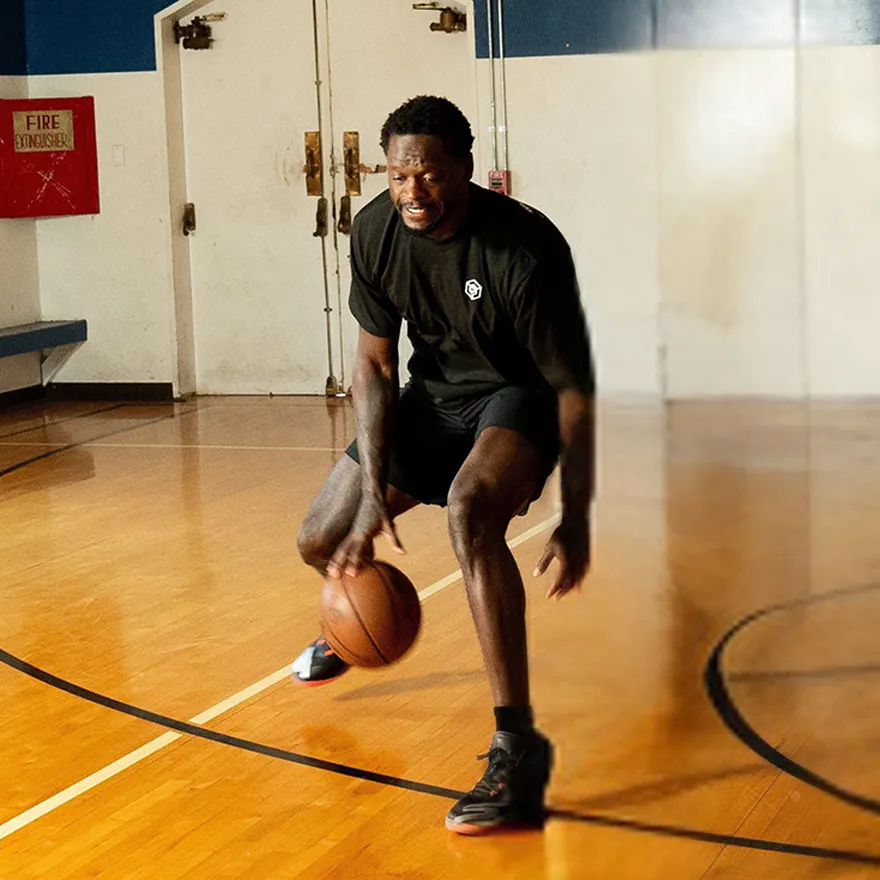 Julius Randle dribbling a basketball in an indoor basketball court.