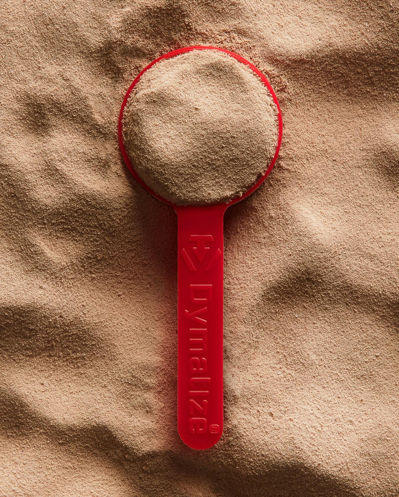 A scoop filled with Dymatize whey protein powder.