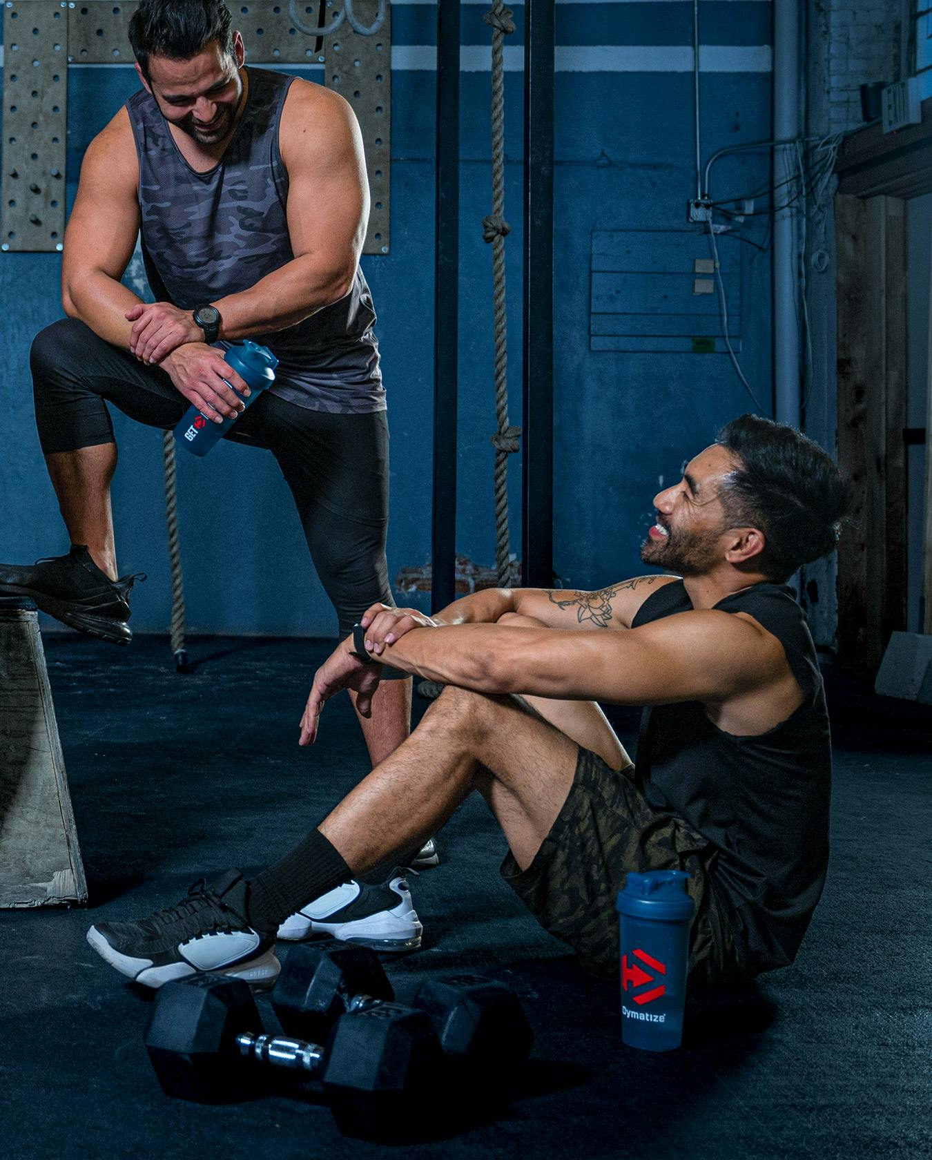 Two male Dymatize Squad athletes conversing and socializing at the gym.