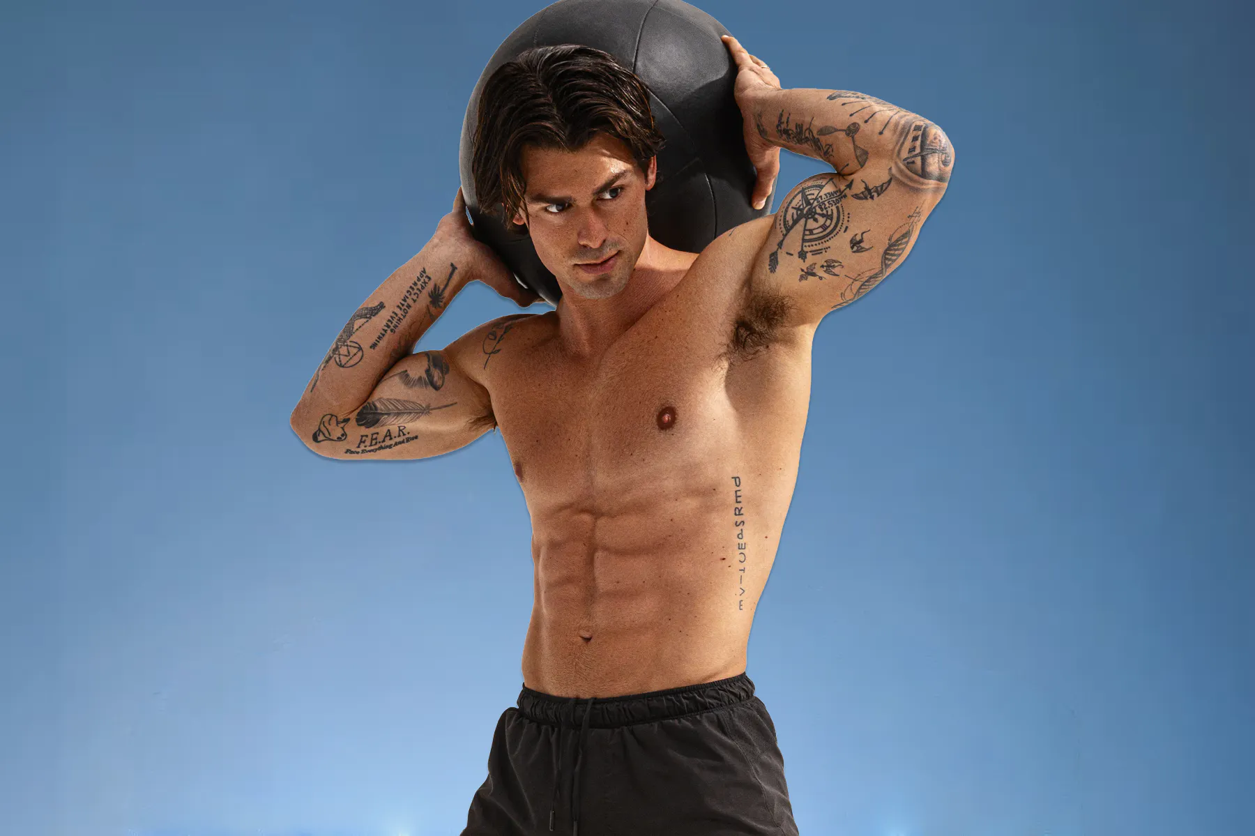 A photo of Garret Miller holding a medicine ball high above his head.