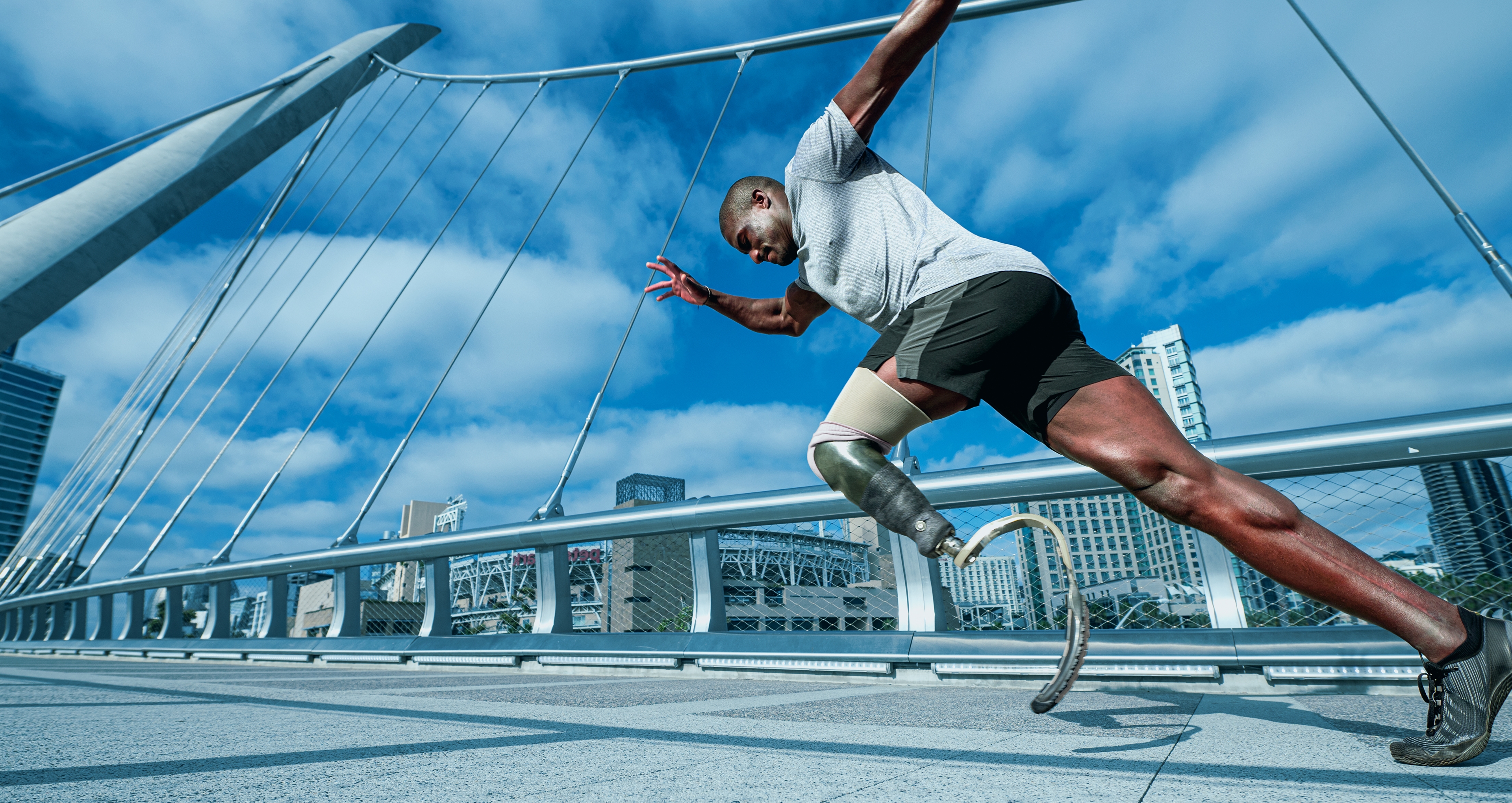 Un hombre con una pierna protésica y ropa de entrenamiento que corre en un puente.