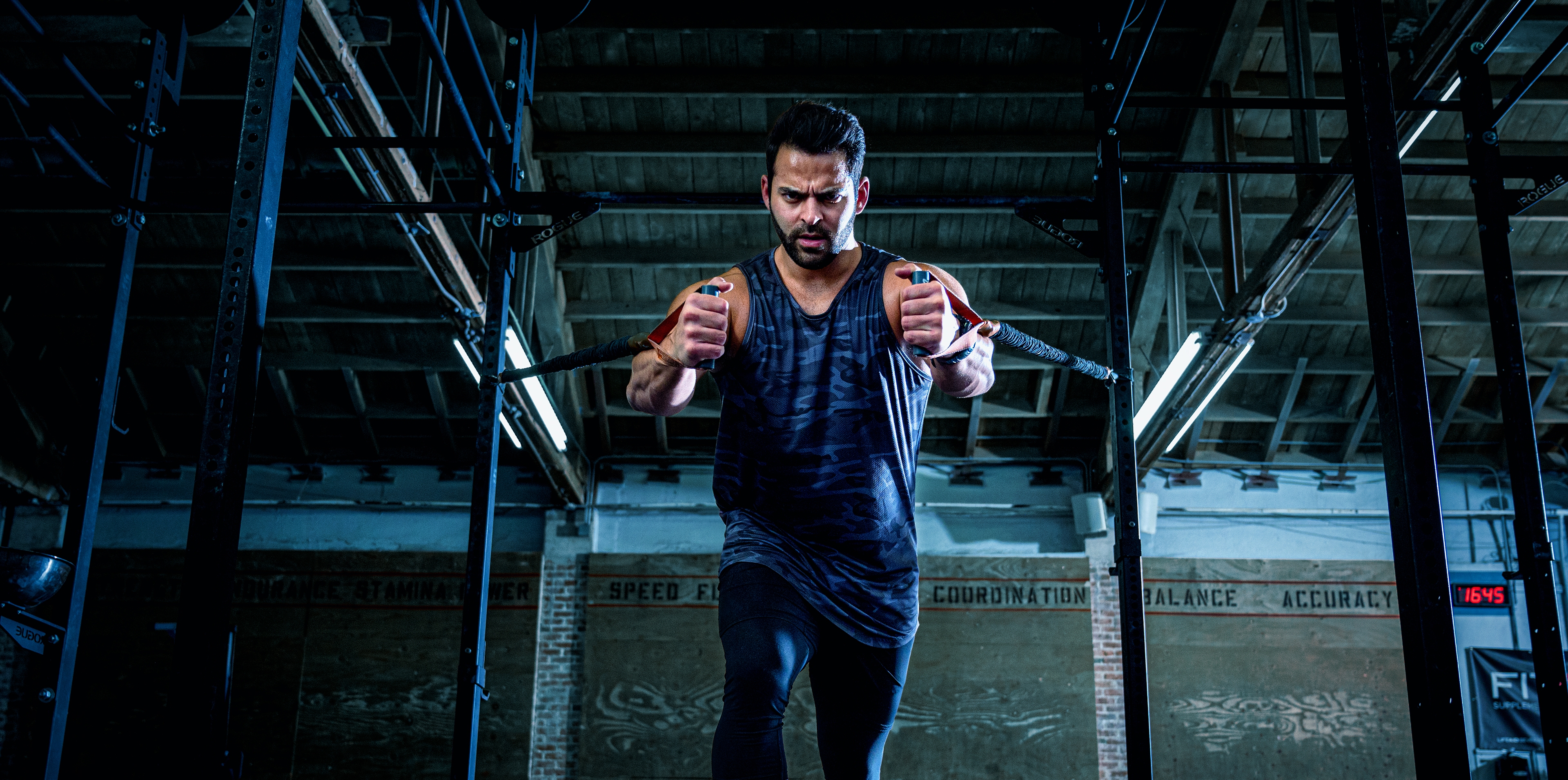 A man in a gym exercising with some pull weights.